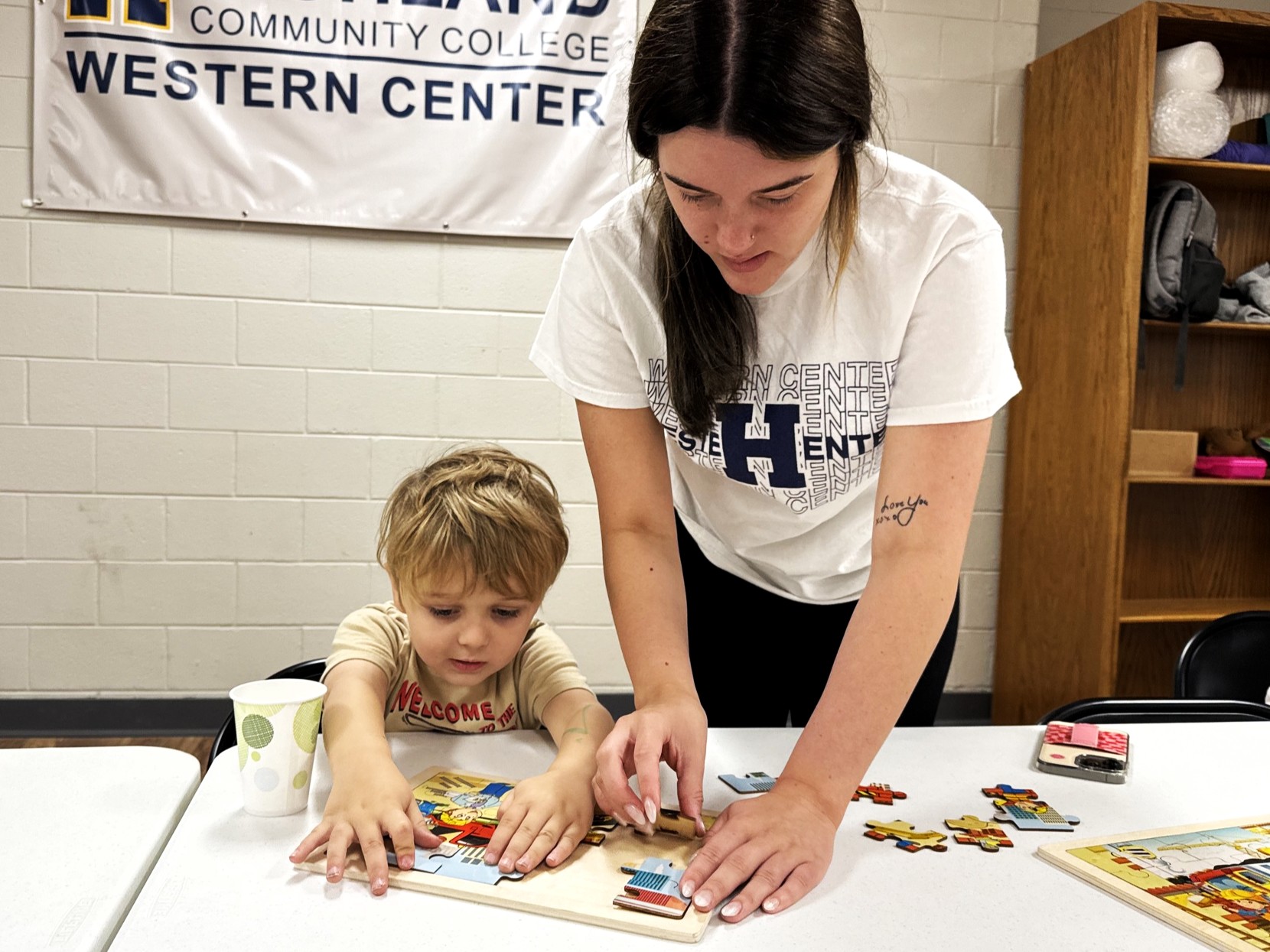 Early Childhood student works on a puzzle with a child.