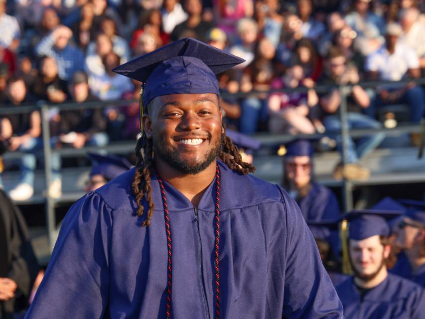 Male student smiles at the camera on graduation day.