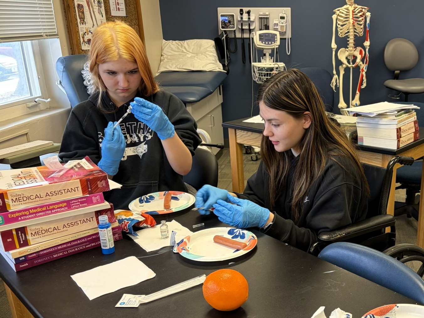 Medical assistant students at the Western Center are focused as they prep syringes for demo application (on hotdogs)