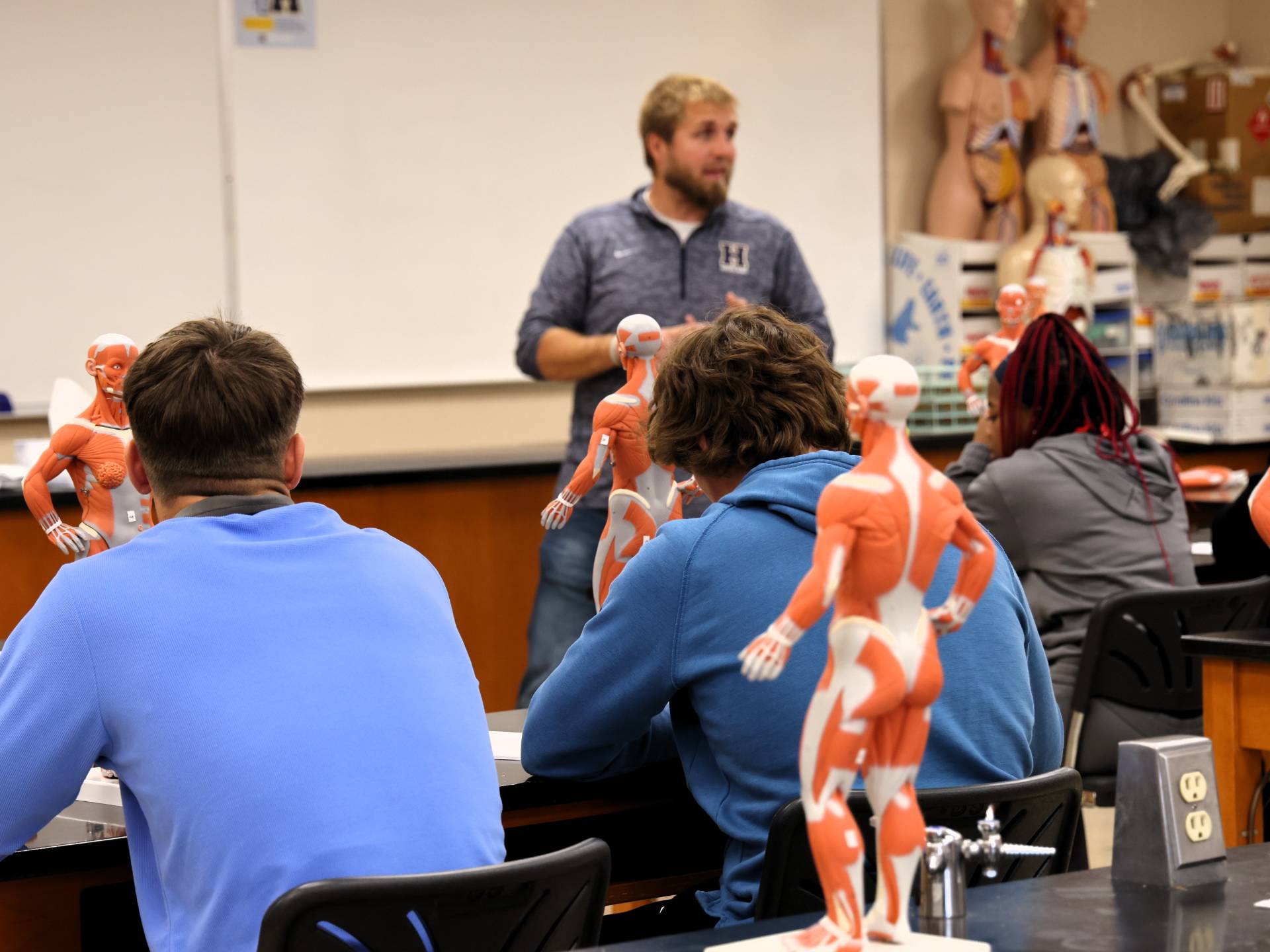 Two students are sitting at a stone table outside