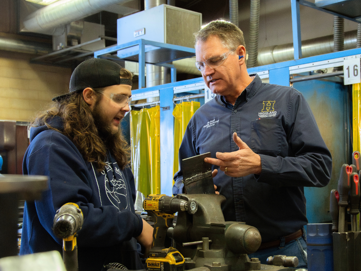 Technical Instructor doing a demonstration in automotive class with a student.
