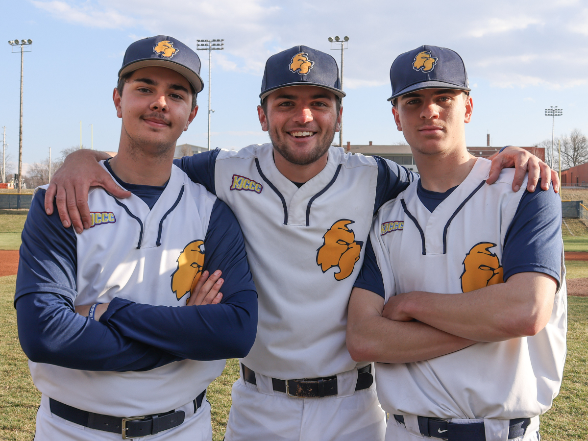 Three baseball players pose shoulder to shoulder for the camera