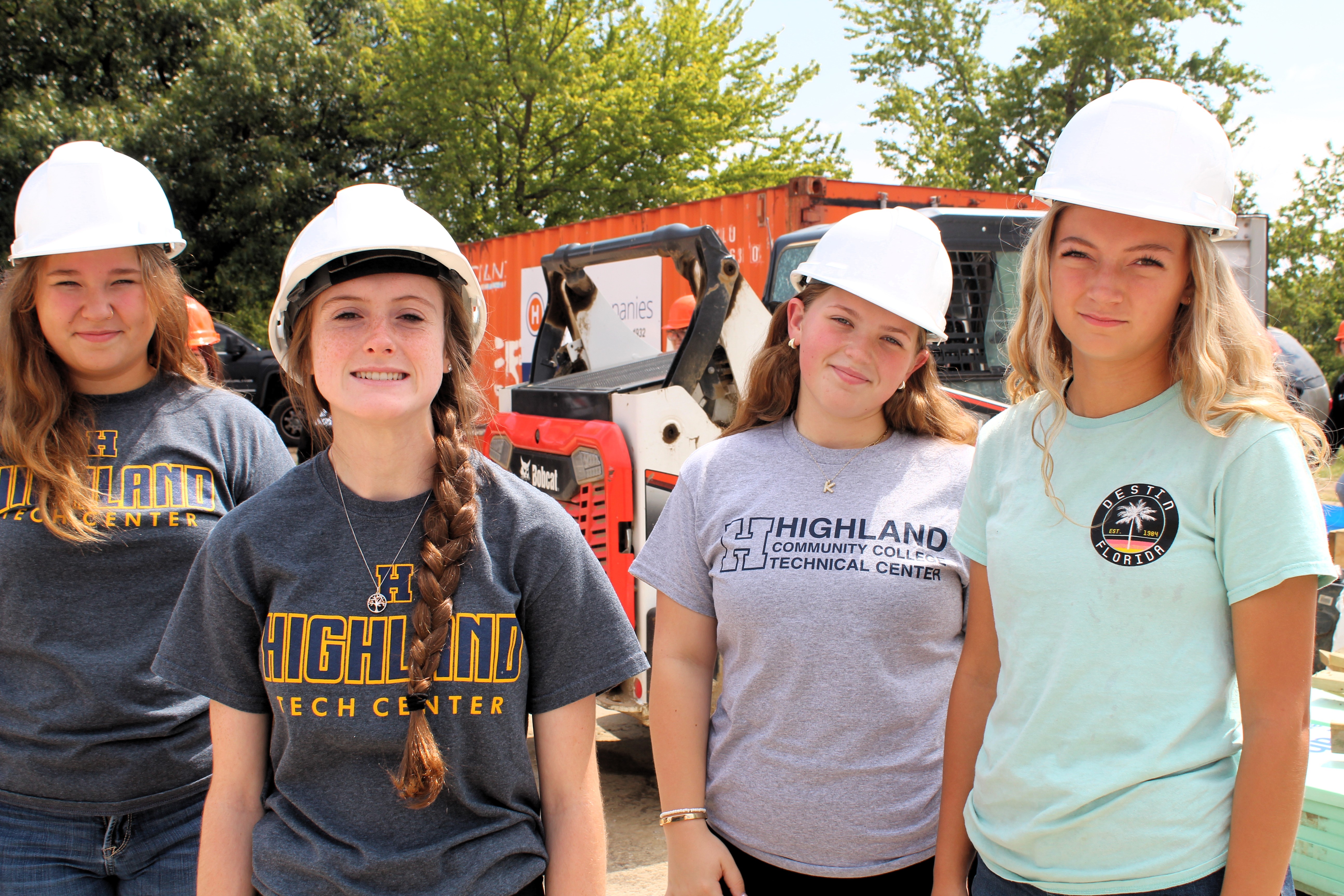 Four students from the technical center on a field trip, pose as a group wearing their hard hats.