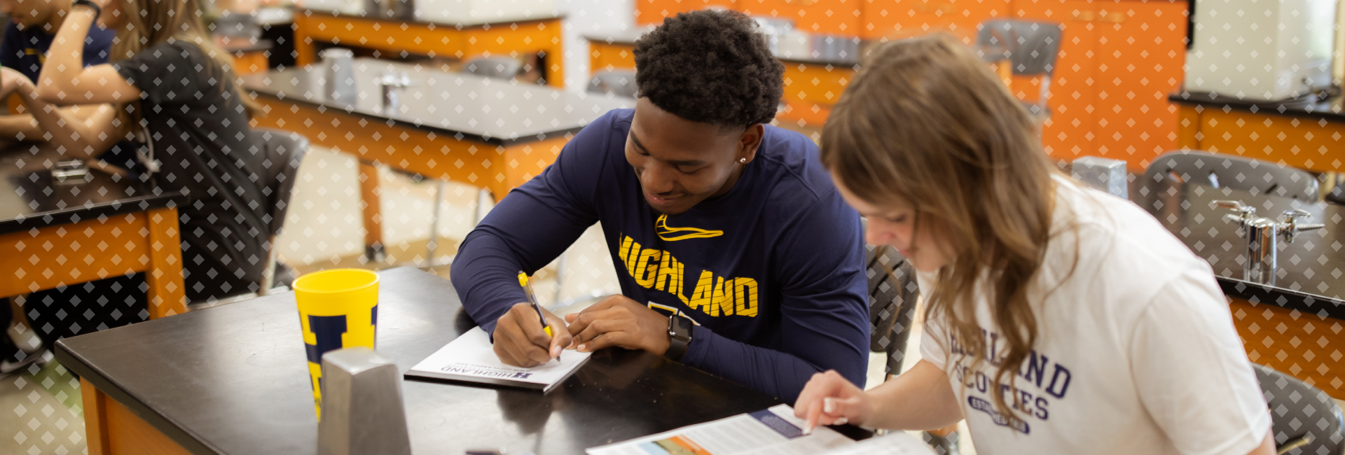 Students sitting in a science class, two students are working on a worksheet together