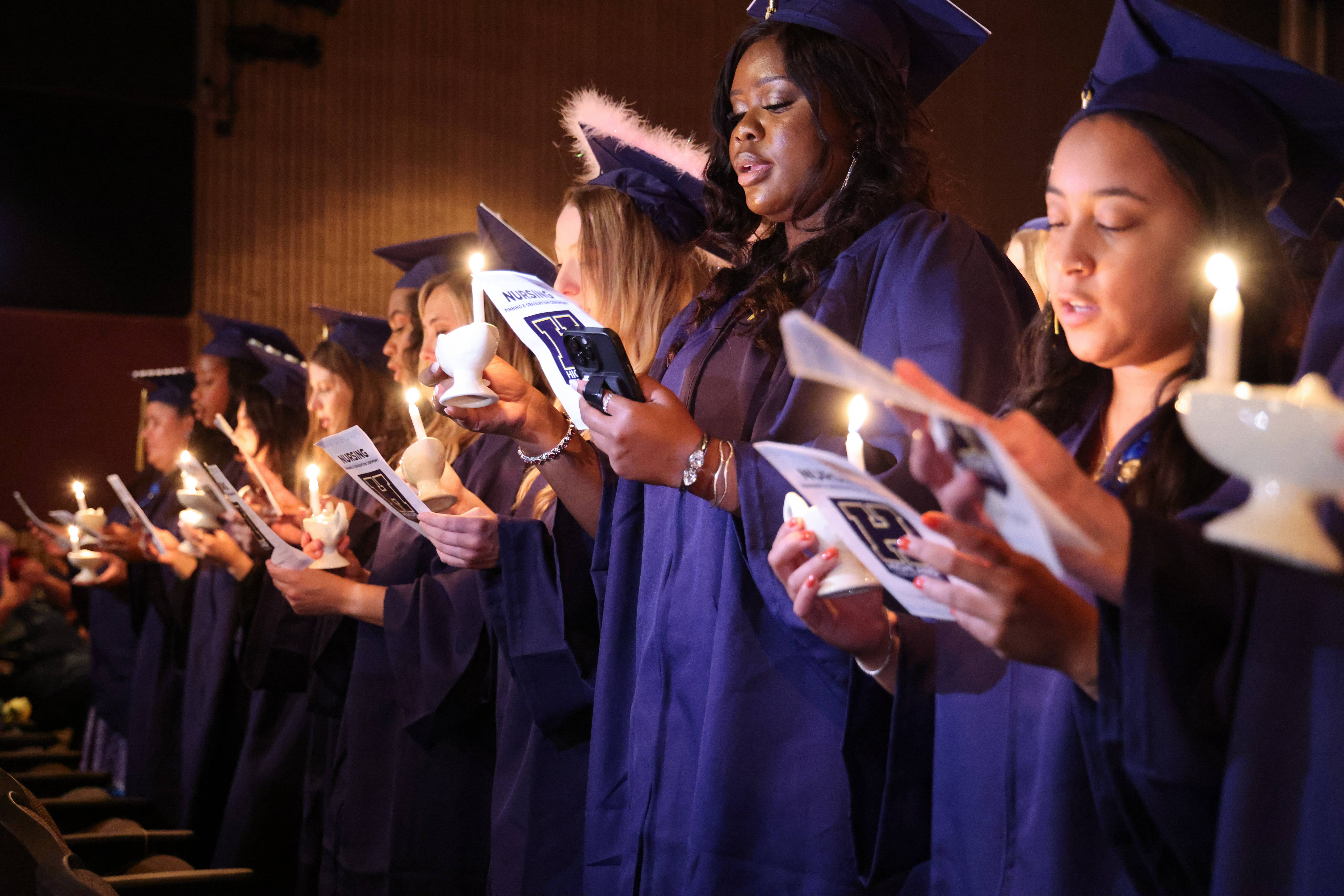 Graduating nursing students during the pinning ceremony stand with candles